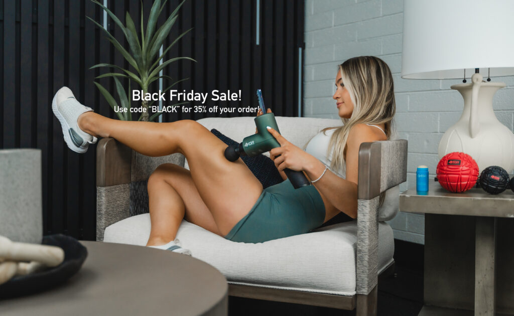 Female athlete using 4KOR foam recovery ball on calf while seated on sofa